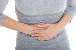 Young casual girl woman is having stomach ache. Over white backg